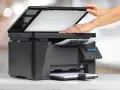 Ręce kładą papier na skanerze pomieszczeń, aby go zeskanować.