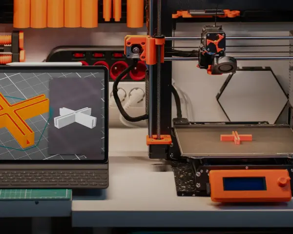 Drukarka 3D drukuje element, a na ekranie tabletu widać model. To ilustracja najczęstszych problemów z drukiem 3d.
